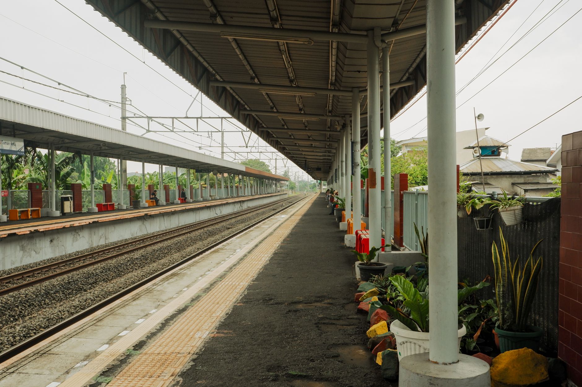 Foto stasiun Bekasi dengan arsitektur modern, tampak platform dan kereta di pagi hari.